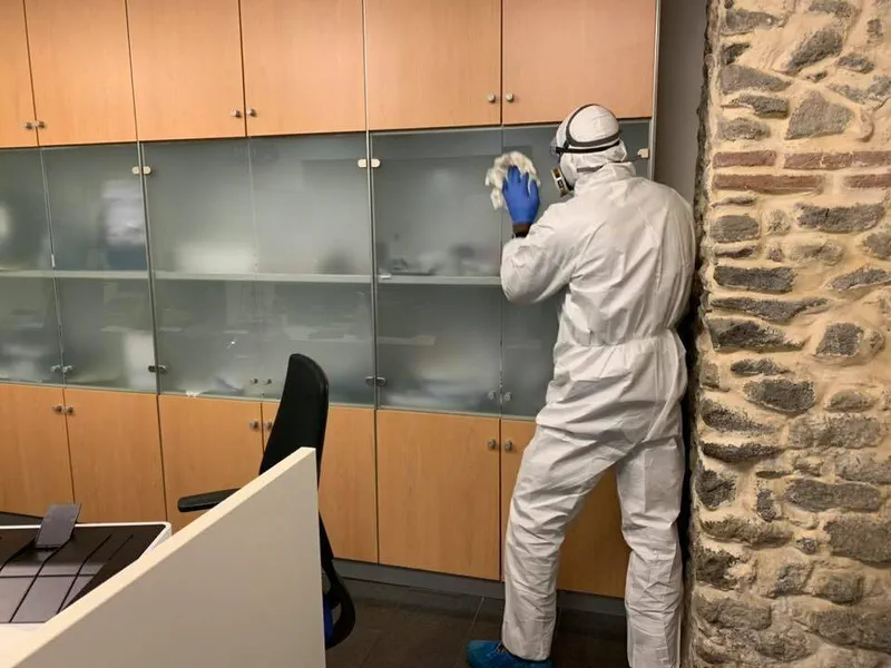 Operatore in tuta protettiva sanifica gli arredi di un ufficio