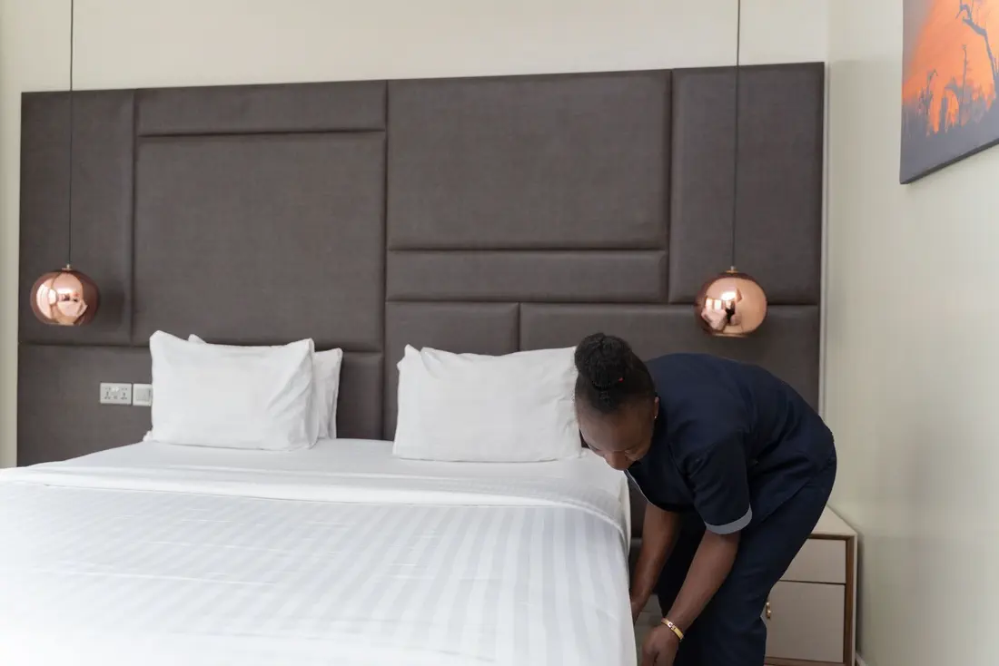 Addetta rifà il letto di una camera d'albergo
