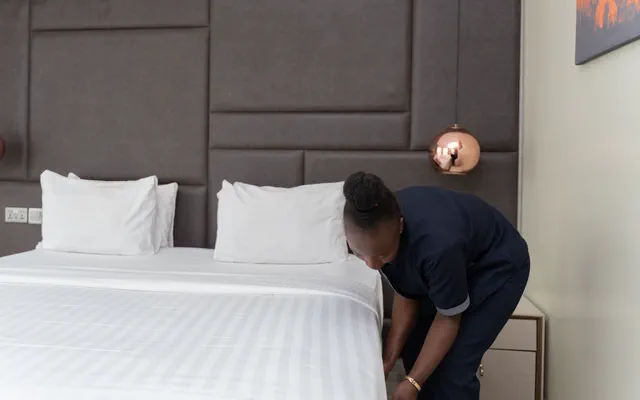 Addetta rifà il letto di una camera d'albergo